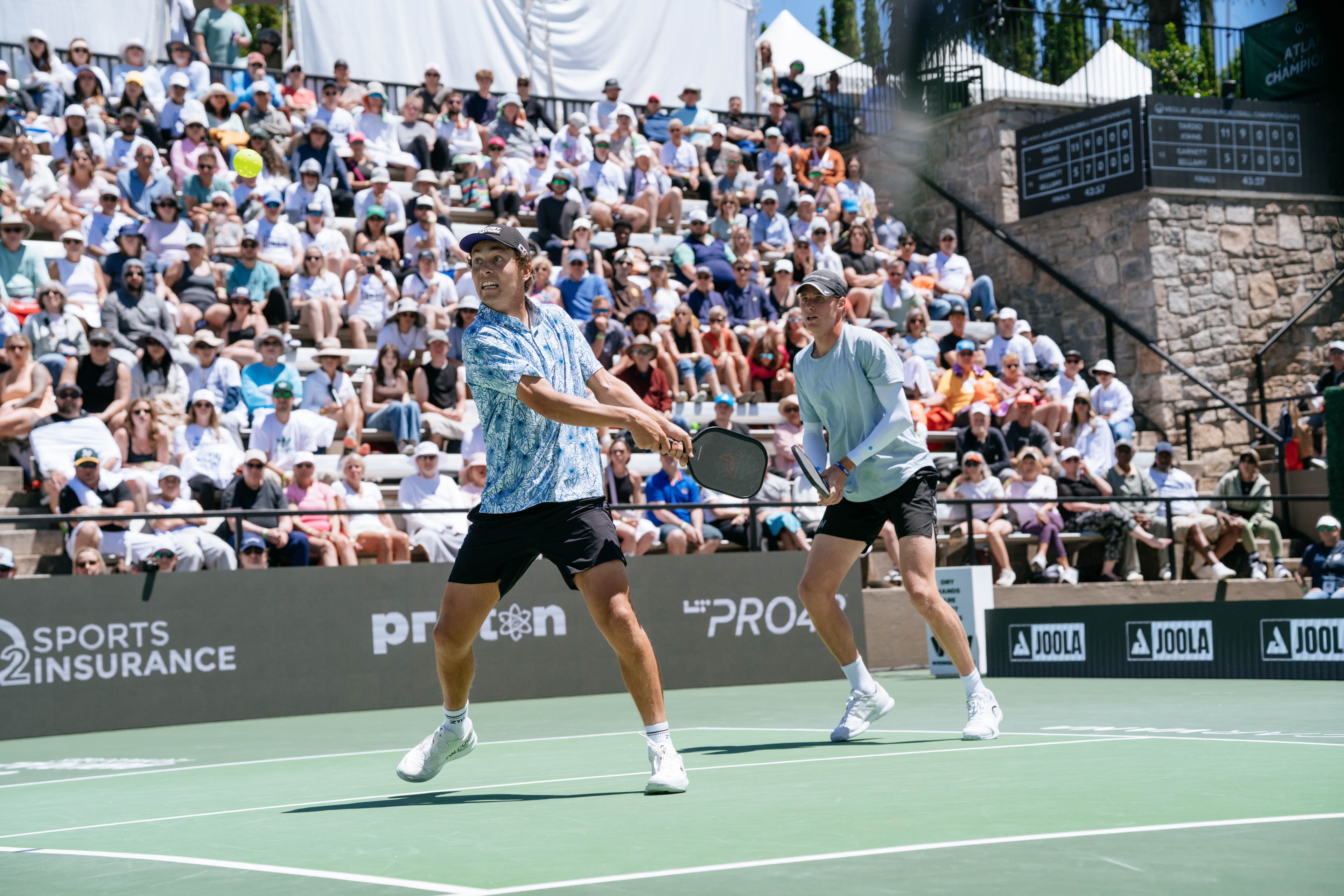 Connor Garnett and his doubles partner tracking a ball in front of a packed pro crowd