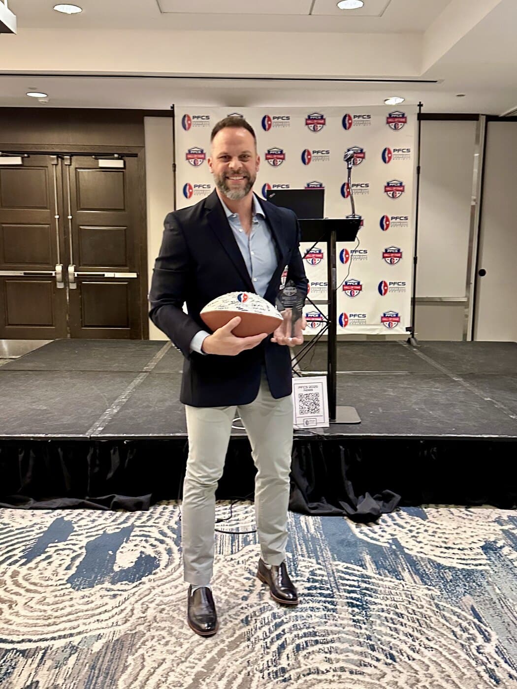 Dr. Joseph Krzemien holding his 2025 Professional Football Chiropractic Society Hall of Fame trophy